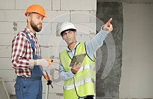 serious builders in hardhats with tablet computer indoors. business, building, teamwork, technology and people