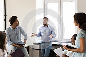 Serious business leader man talking to diverse group of employees