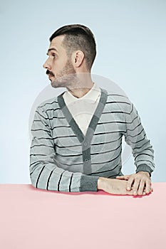 Serious business man sitting at a table on a blue background