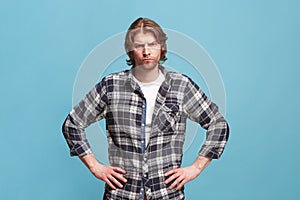 The serious business man standing and looking at camera against bllue background.