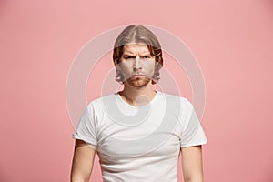 The serious business man standing and looking at camera against pink background.