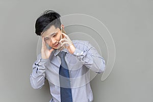 Serious business man talking on mobile phone on gray background