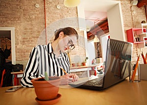 Serious business woman at desk with laptop writing in office