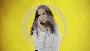 Serious business woman talking mobile phone on yellow background. Portrait of young businesswoman calling phone in