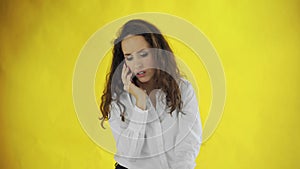 Serious business woman talking mobile phone on yellow background. Portrait of young businesswoman calling phone in