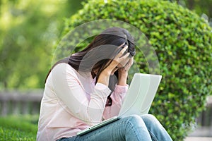 Serious business woman work hard with serious problem in a public park. Working on laptop outdoors.