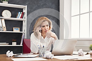 Serious business woman at work talking on phone