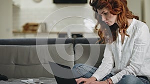 Serious business woman working laptop computer at remote workplace.