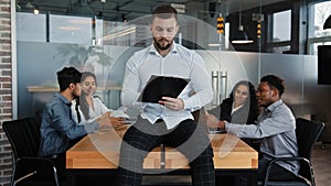 Serious businessman boss leader man sit on desk table in office check paperwork pensive write with folder business