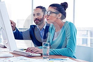 Serious businessman and businesswoman discussing over computer