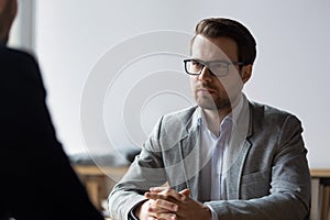 Serious businessman with clasped hands looking at opponent at negotiations