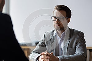 Serious businessman with clasped hands looking at opponent at negotiations photo