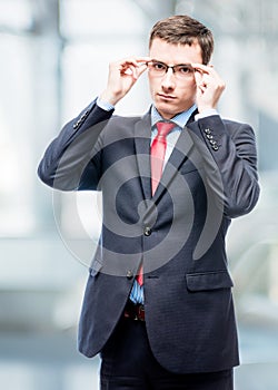 Serious businessman corrects glasses portrait