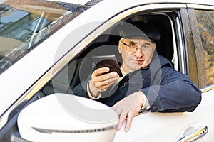 serious businessman driving his car and looking at smartphone