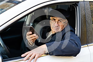 serious businessman driving his car and looking at smartphone