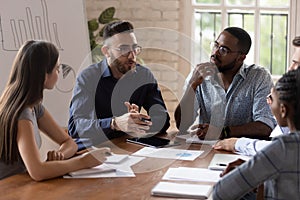 Serious businessman executive talk to diverse staff at briefing table