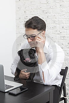 Serious businessman and his lovely pet pug working on laptop