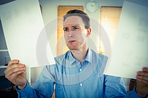 Serious businessman holding two paper sheets