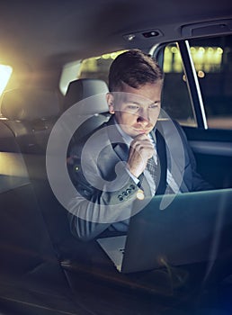 Serious businessman in moving car checking his working