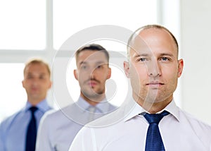 Serious businessman in office with team on back