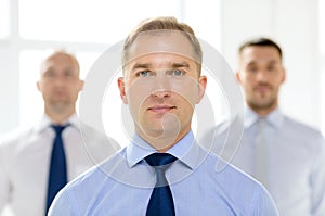 Serious businessman in office with team on back
