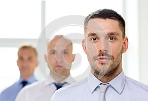 Serious businessman in office with team on back