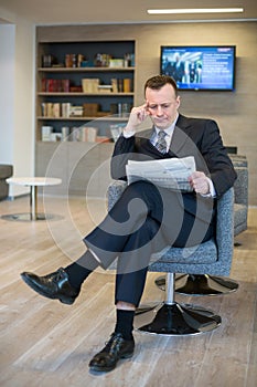 A serious businessman reading a newspaper photo