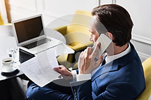 Serious businessman speaking by phone in workplace