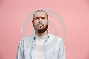 The serious businessman standing and looking at camera against pink background.