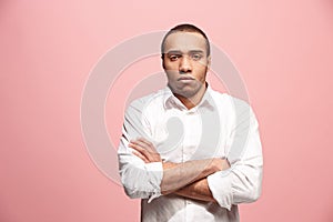 The serious businessman standing and looking at camera against pink background.