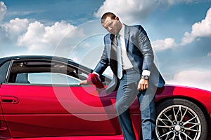 Serious businessman standing near car