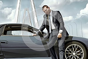 Serious businessman standing near car