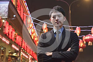 Serious Businessman standing on the street, red lanterns in the background