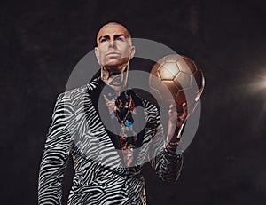 Serious businessman in suit posing with golden soccer ball