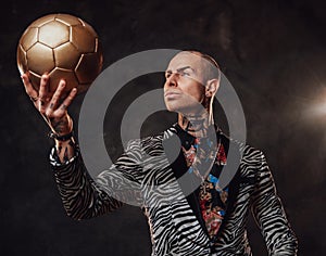 Serious businessman in suit posing with golden soccer ball