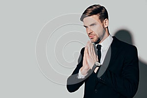 Serious businessman in suit with pray gesture