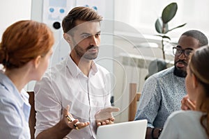 Serious businessman talking with group of business partners at meeting