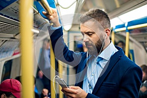 Serious businessman travelling to work. Standing inside underground wagon. photo