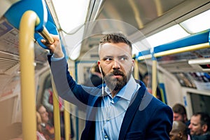 Serious businessman travelling to work. Standing inside underground wagon.