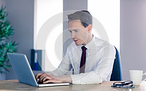 Serious businessman typing on laptop