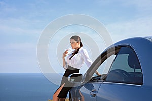 Serious businessman woman drinking coffee near the car