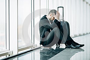 Serious businessman worrying something, sitting and touch his head at the airport terminal. Businessman miss his flight. Young man