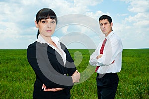 Serious businesspeople standing on green meadow