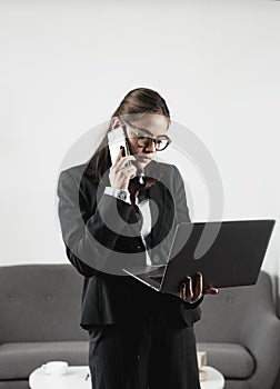 Serious businesswoman answering telephone at office desk. Young business woman freelancer or ceo employee working in