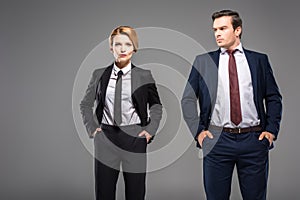 serious businesswoman and businessman posing with hands in pockets