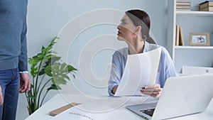 Serious businesswoman dismissing employee for paperwork error