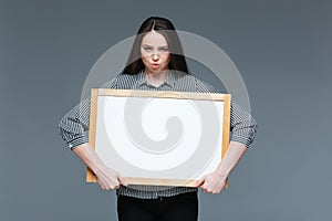 Serious businesswoman holding blank board