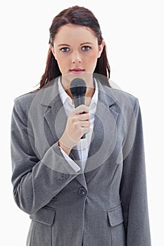 A serious businesswoman holding a microphone