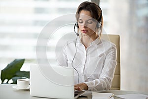 Serious businesswoman with laptop in headset making online confe