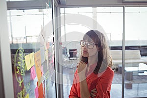 Serious businesswoman looking at adhesive notes in office